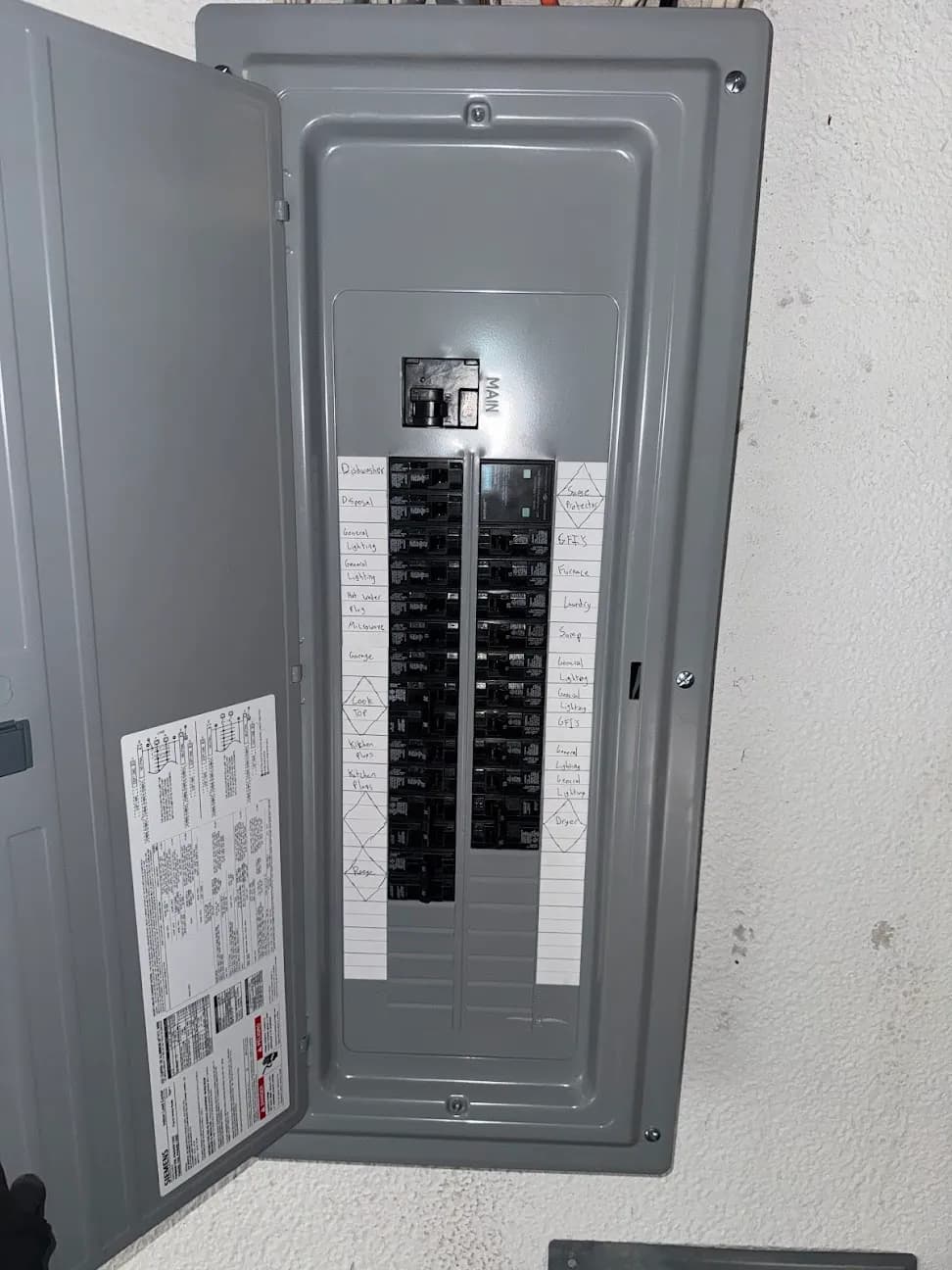 An open residential breaker panel with a labeled circuit directory on the inside of the door